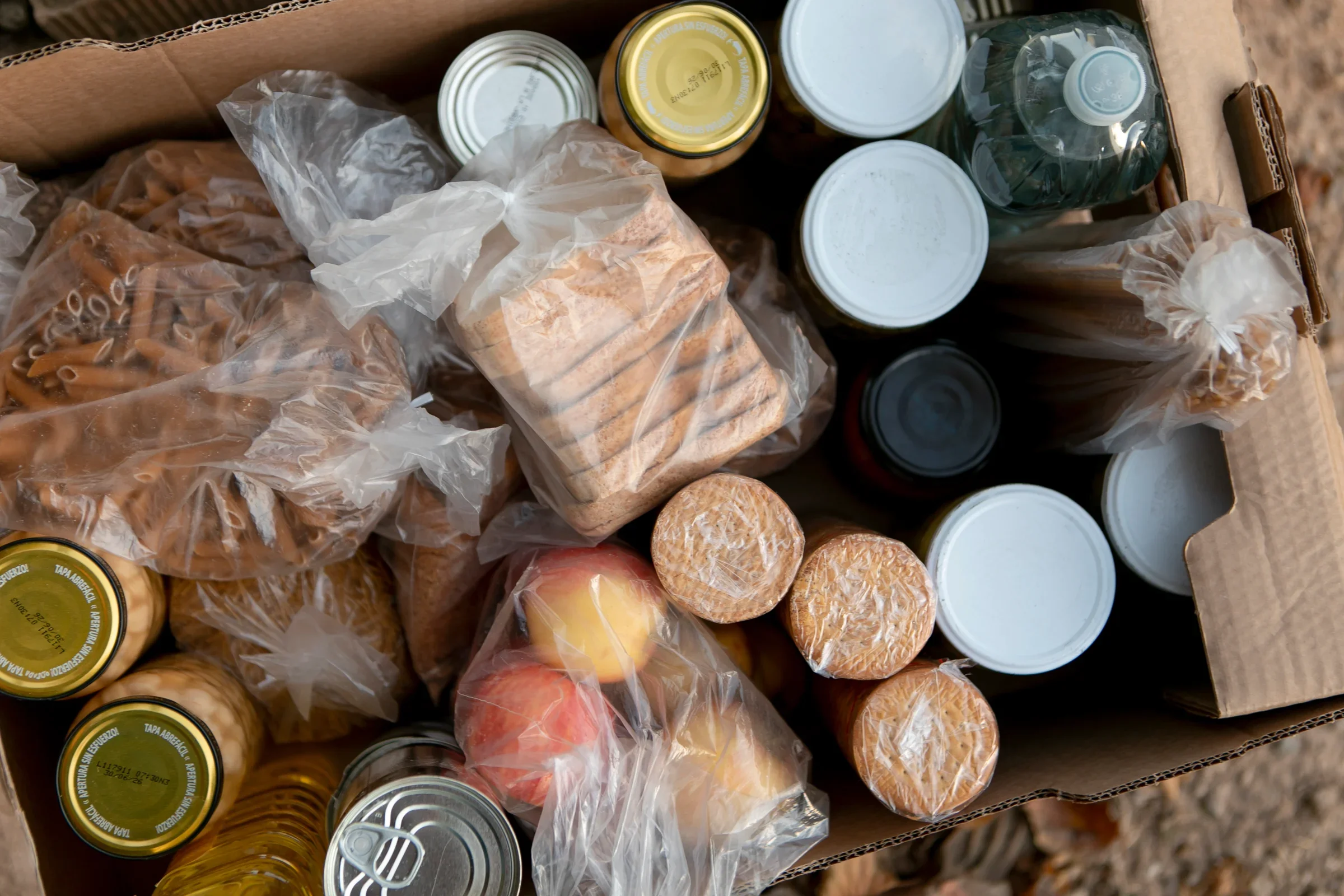 A collection bin overflowing with canned goods outside a shop.