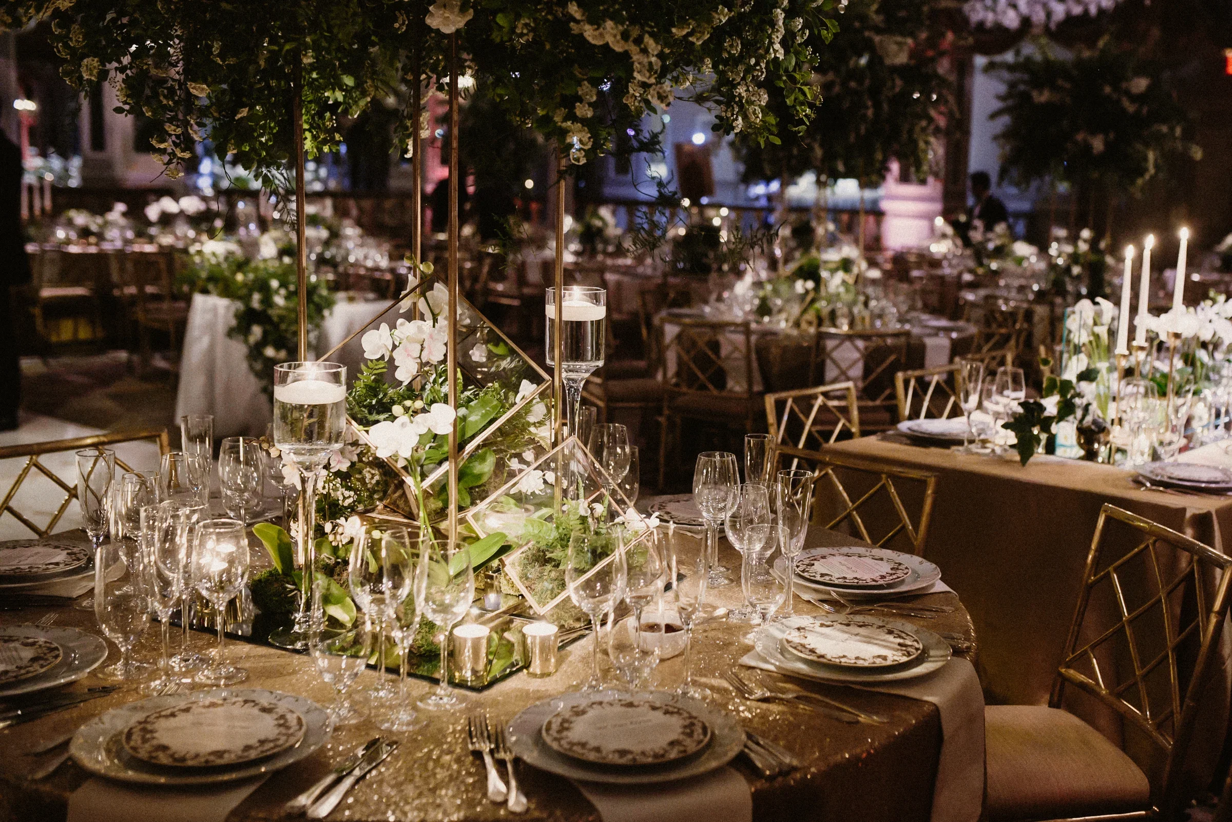 Elegant round dinner tables with candles and centerpieces of vegetables and flowers.